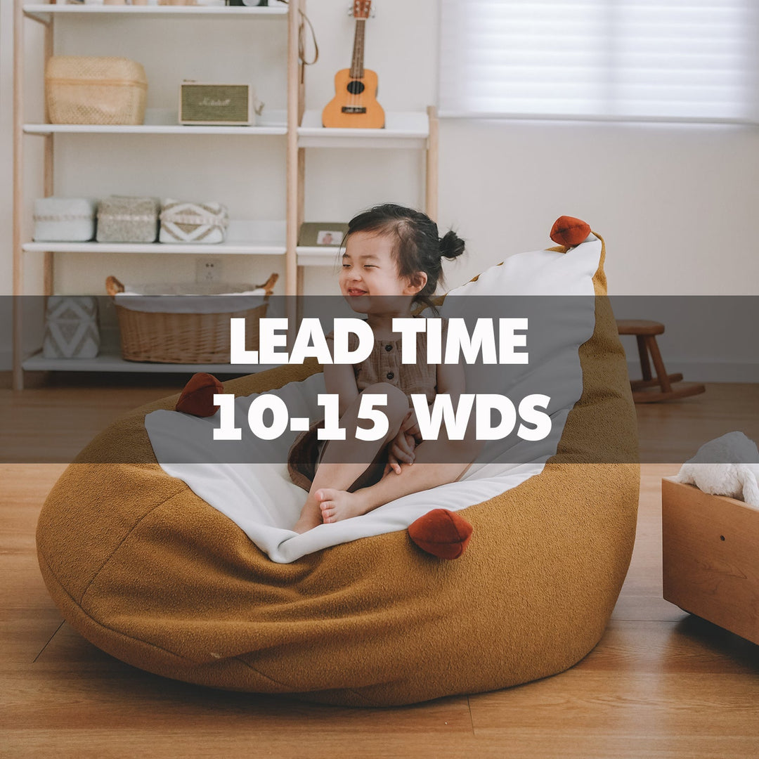 Smiling child sitting on a cozy brown bean bag chair in a bright playroom, highlighting Loft Home’s 10–15 working days lead time collection for made-to-order kids’ furniture.