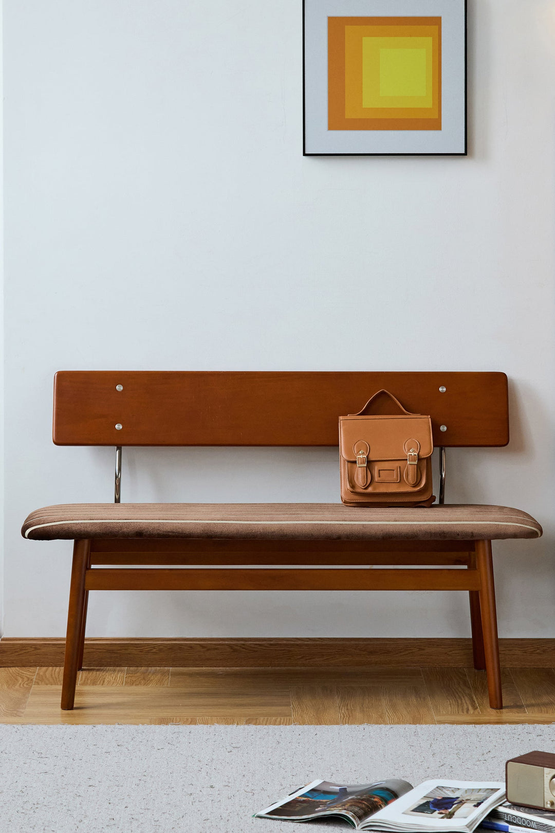 Brown fabric bench with a bag and a magazine against a white wall. Loft Home Benches collection