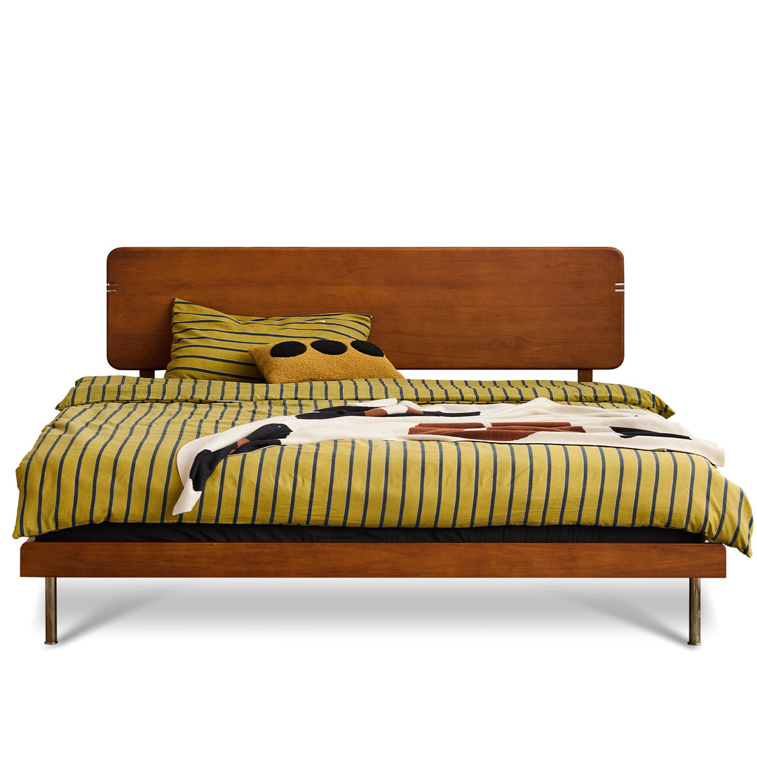 Wooden bed with striped yellow and green bedding on a white background