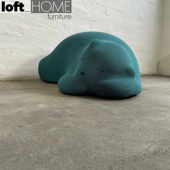 Contemporary knit fabric ottoman resting bear in panoramic view.
