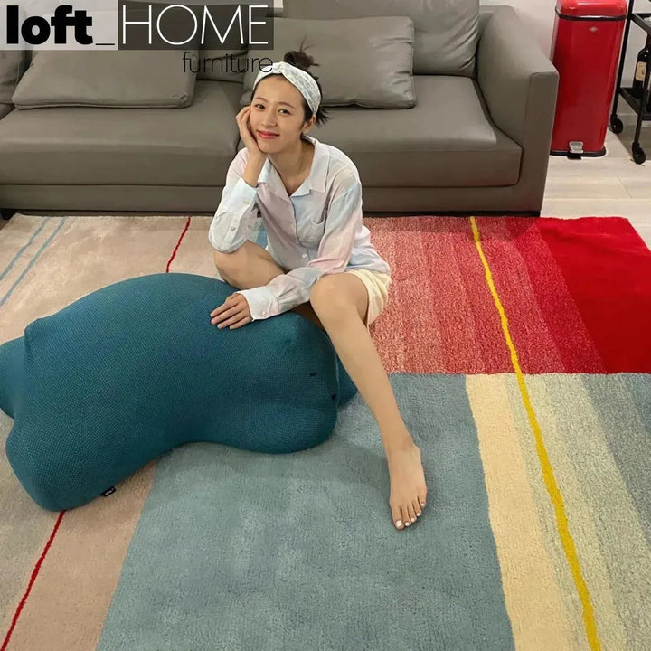 Contemporary knit fabric ottoman resting bear with context.