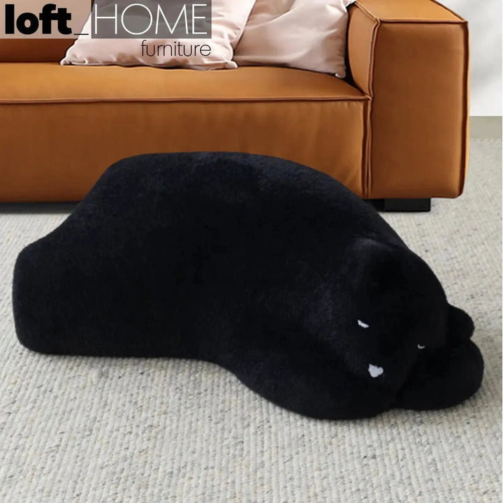 Contemporary velvet ottoman resting bear black color swatches.
