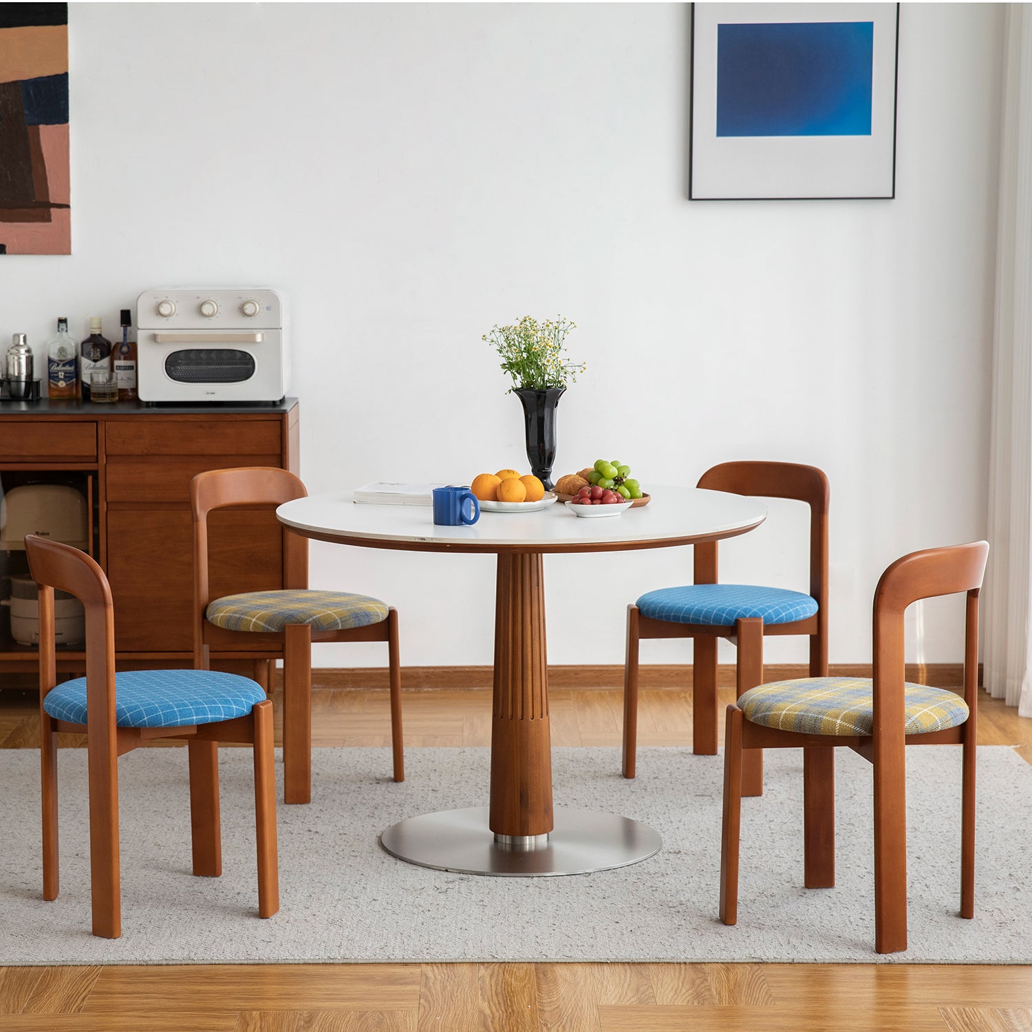 Dining area with wooden table and chairs in a room with white walls and a blue abstract painting.